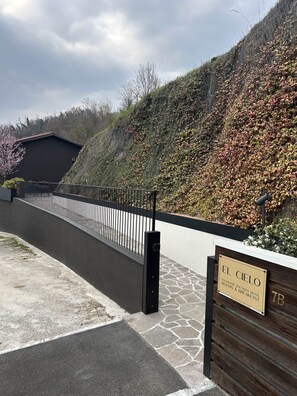 A gated entrance to a hotel with a stone pathway leading to a black-roofed building.