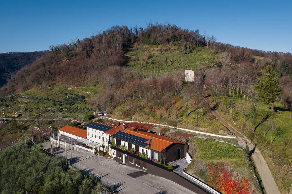A building with a red roof, surrounded by a parking area and a hilly landscape.