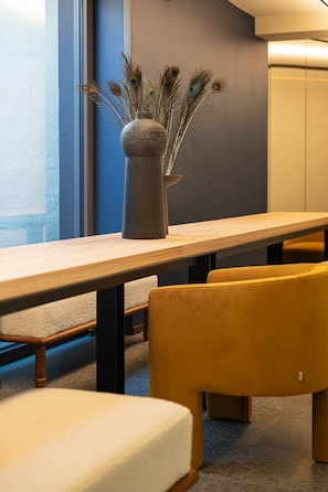 Un intérieur moderne avec une longue table, des chaises jaunes et un vase contenant des plantes séchées.