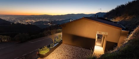 A building with a sign 'EL CIELO' on a hillside with a view of a cityscape at dusk.