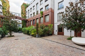 A courtyard with brick flooring, a covered walkway, and a variety of plants. - Luxury apartment with vertical garden • Bastille (Paris)