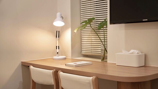 Uma mesa com uma luminária, uma planta e uma caixa de lenços.
