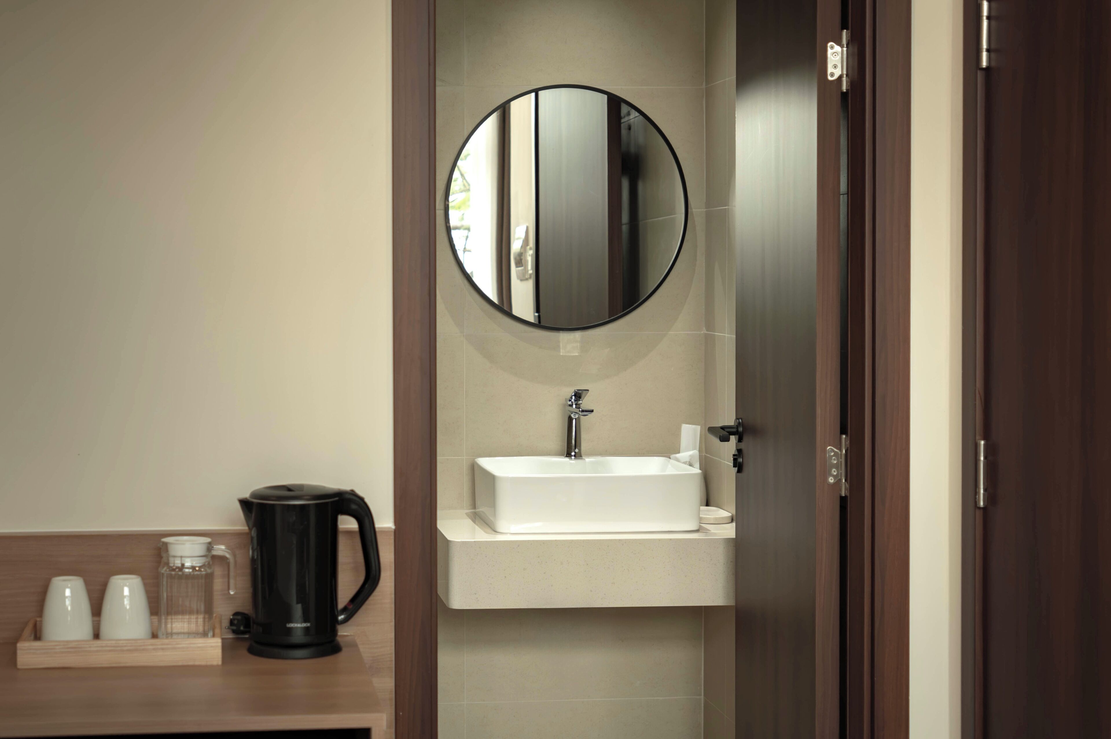 A bathroom with a white sink, a round mirror, and a coffee maker on the counter.