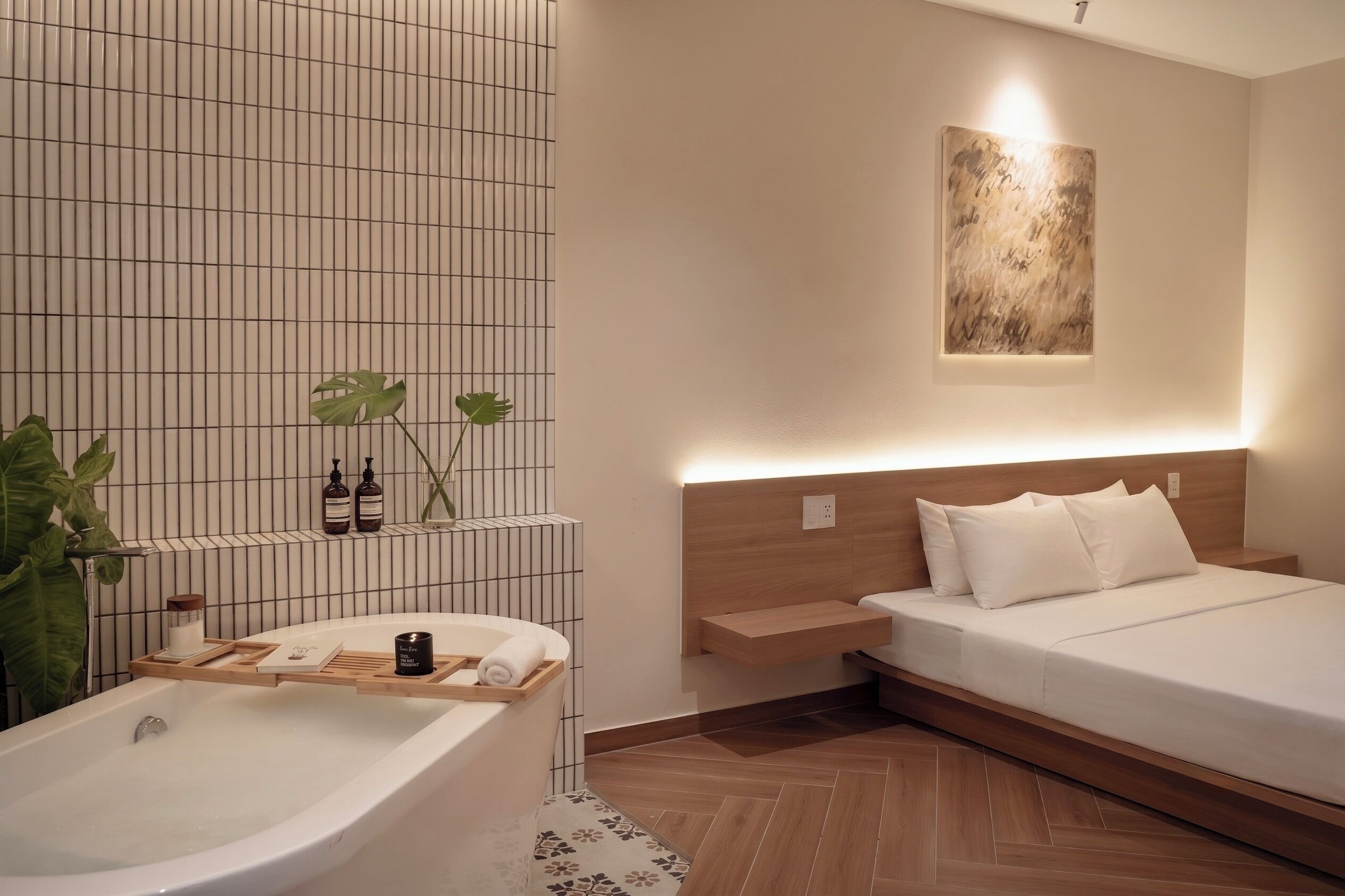Un baño moderno con una bañera independiente, un estante de madera con artículos de aseo y una planta verde grande.