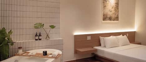 A modern bathroom with a freestanding bathtub, a wooden shelf with toiletries, and a large green plant.