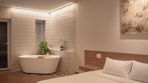 Uma casa de banho moderna com uma banheira independente, área de duche e sanita.