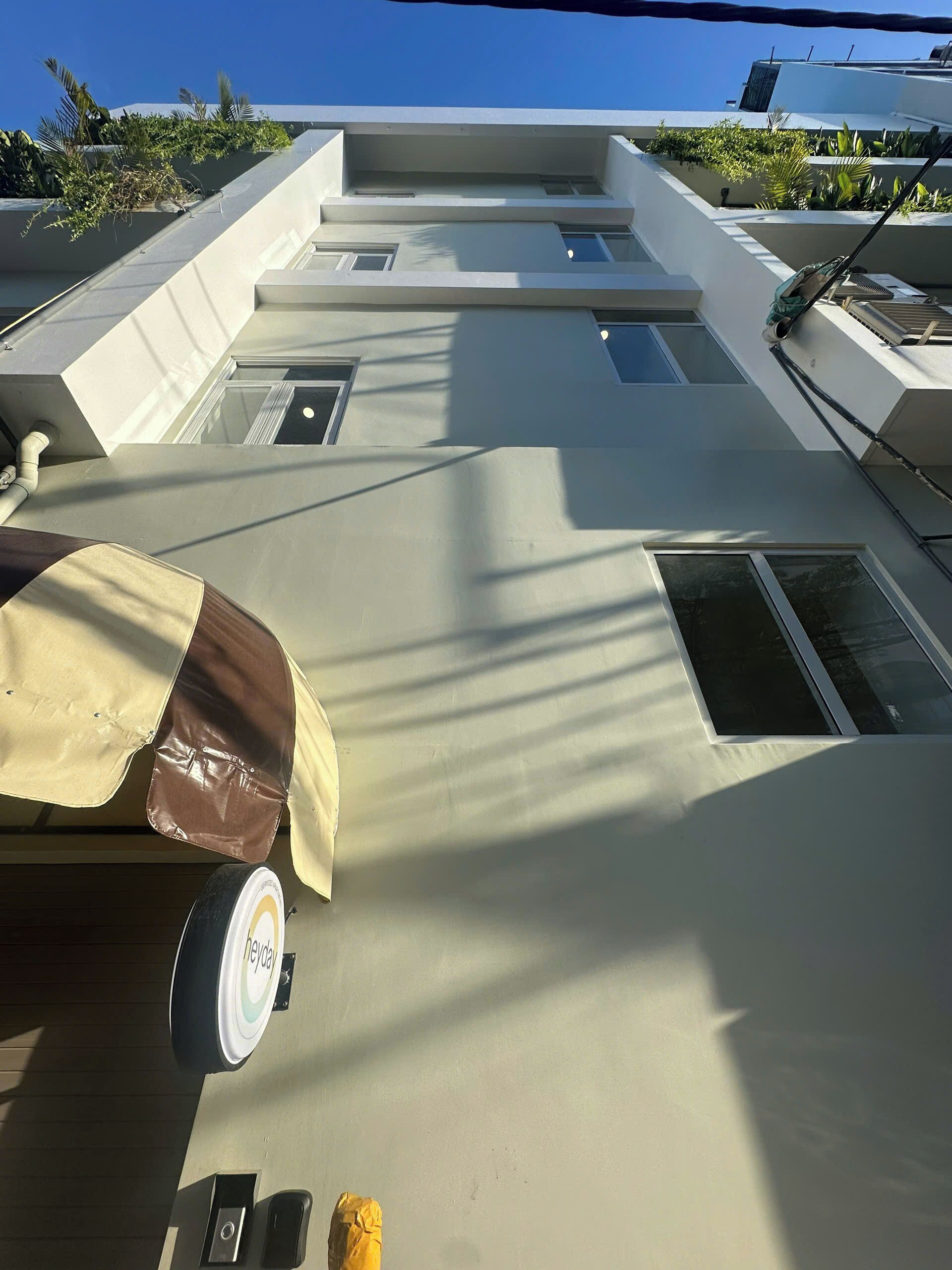 A modern building with a flat roof, multiple windows, and a covered area with a wheelchair-accessible ramp.