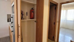 Una cucina moderna con mobili in legno, forno integrato e estintore sul piano di lavoro.