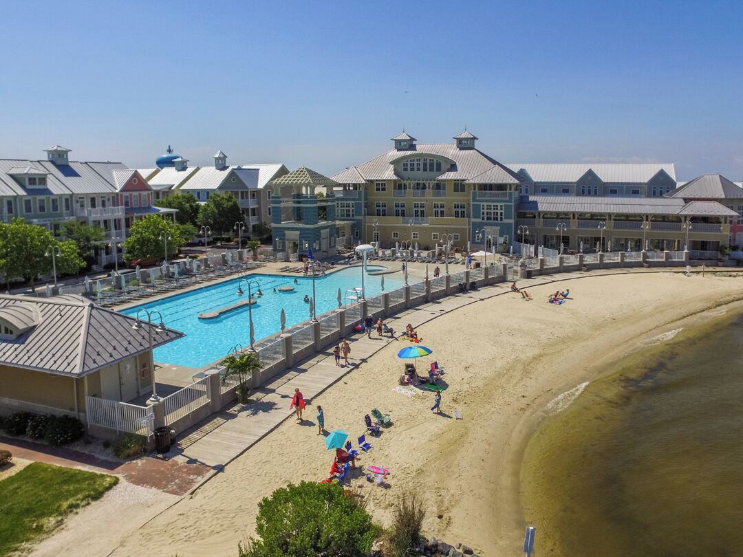 Een resort met een zwembad, strand en meerdere gebouwen in verschillende bouwstijlen.