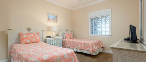 Un dormitorio con dos camas, un ventilador de techo, una ventana con vidrieras decorativas y un aparador.
