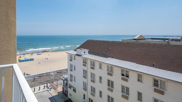 Um hotel à beira-mar com vista para o oceano, uma praia de areia e um edifício com várias janelas.