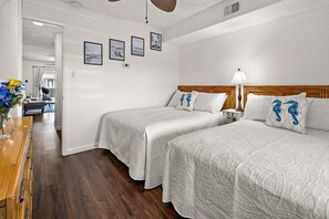 Ein Hotelzimmer mit zwei Betten, einem Holzschrank und einem Schreibtisch mit Blumenvase.