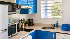 Une cuisine compacte équipée d’un lave-linge, d’une machine à café et d’un four à micro-ondes.