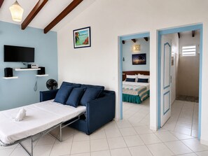 Ein Schlafzimmer mit Bett, Fernseher, Schreibtisch und Stuhl.