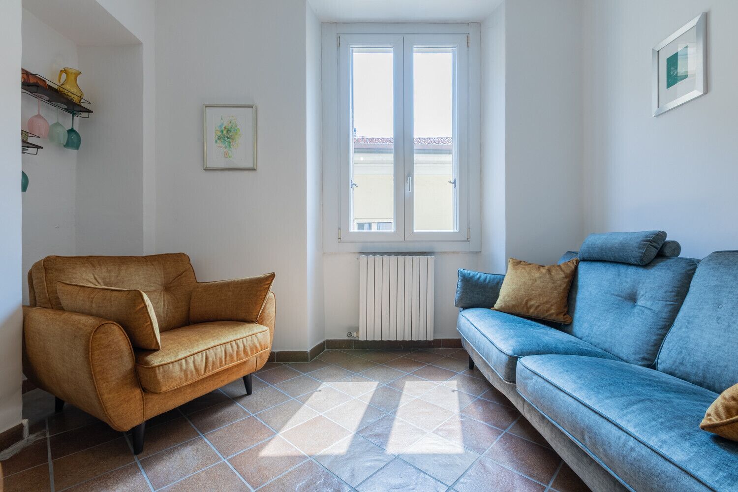 A living room with two sofas, a radiator, and a window.