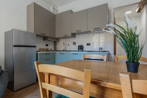 Eine moderne Küche mit einem Edelstahl-Kühlschrank, hellblauen Schränken, einem Holztisch und einem Topfpflanzen.