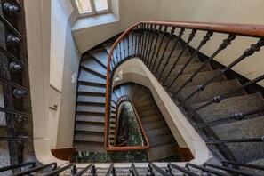 A spiral staircase with a wooden handrail and black balusters. - Finestra Sulle Porte Palatine by Wonderful Italy (Turin)
