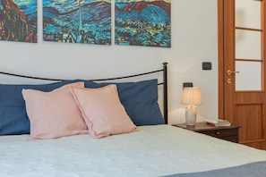 A bedroom with a bed, pillows, a bedside table with a lamp, and wall art. - Finestra Sulle Porte Palatine by Wonderful Italy (Turin)