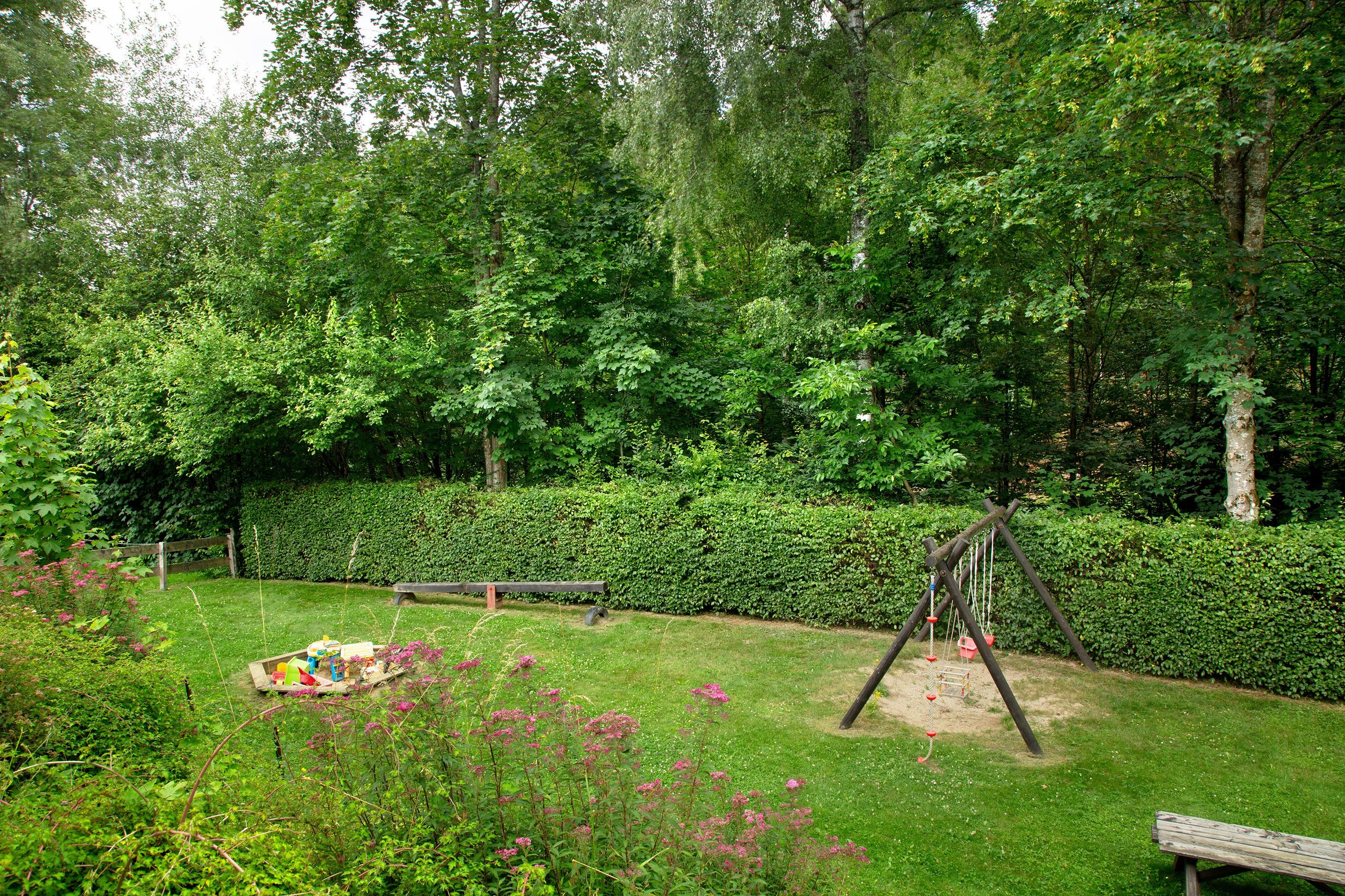 En trädgård med en gunga, en bänk och ett picknickbord.