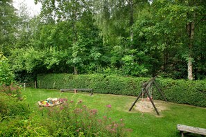 En trädgård med en gunga, en bänk och ett picknickbord.