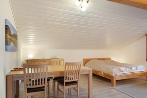 Un dormitorio con una cama de madera, un escritorio con silla y una lámpara en el techo.