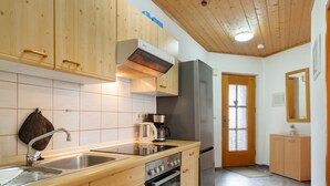 A kitchen with wooden cabinets, a stainless steel sink, a coffee maker, and a refrigerator. - Apartment Hauzenberg with Indoor & Outdoor Pool, Sauna, Lake View (Hauzenberg)