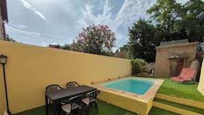 Un pati amb piscina, taula i caires, i una petita zona de jardí.