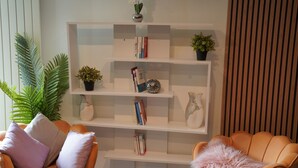 Uma sala de estar moderna com dois poltronas laranja, uma estante branca e vasos decorativos.