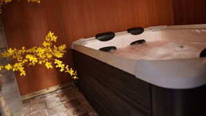 Uma banheira de hidromassagem com água, cercada por painéis de madeira e piso de azulejo.