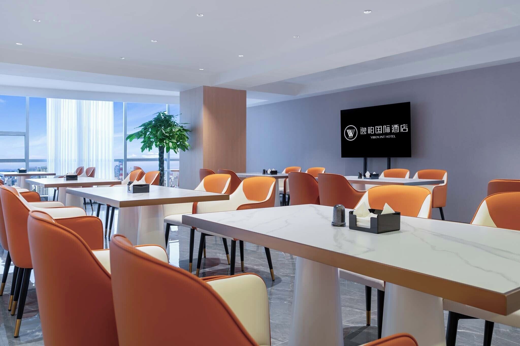 Une salle de conférence moderne, située dans un hôtel, équipée de plusieurs tables et chaises, d’un grand écran et offrant une vue sur la ville.