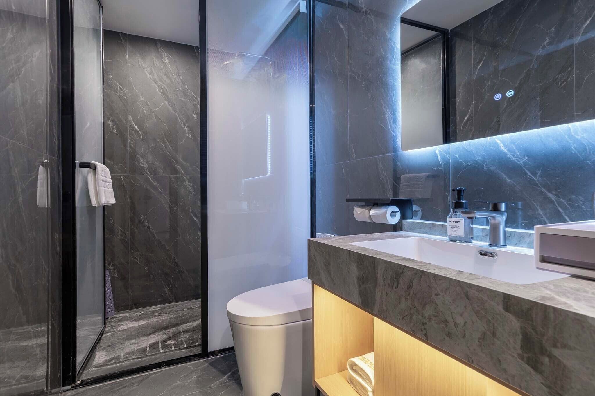 A modern bathroom with a glass shower enclosure, a toilet, and a vanity with a mirror.