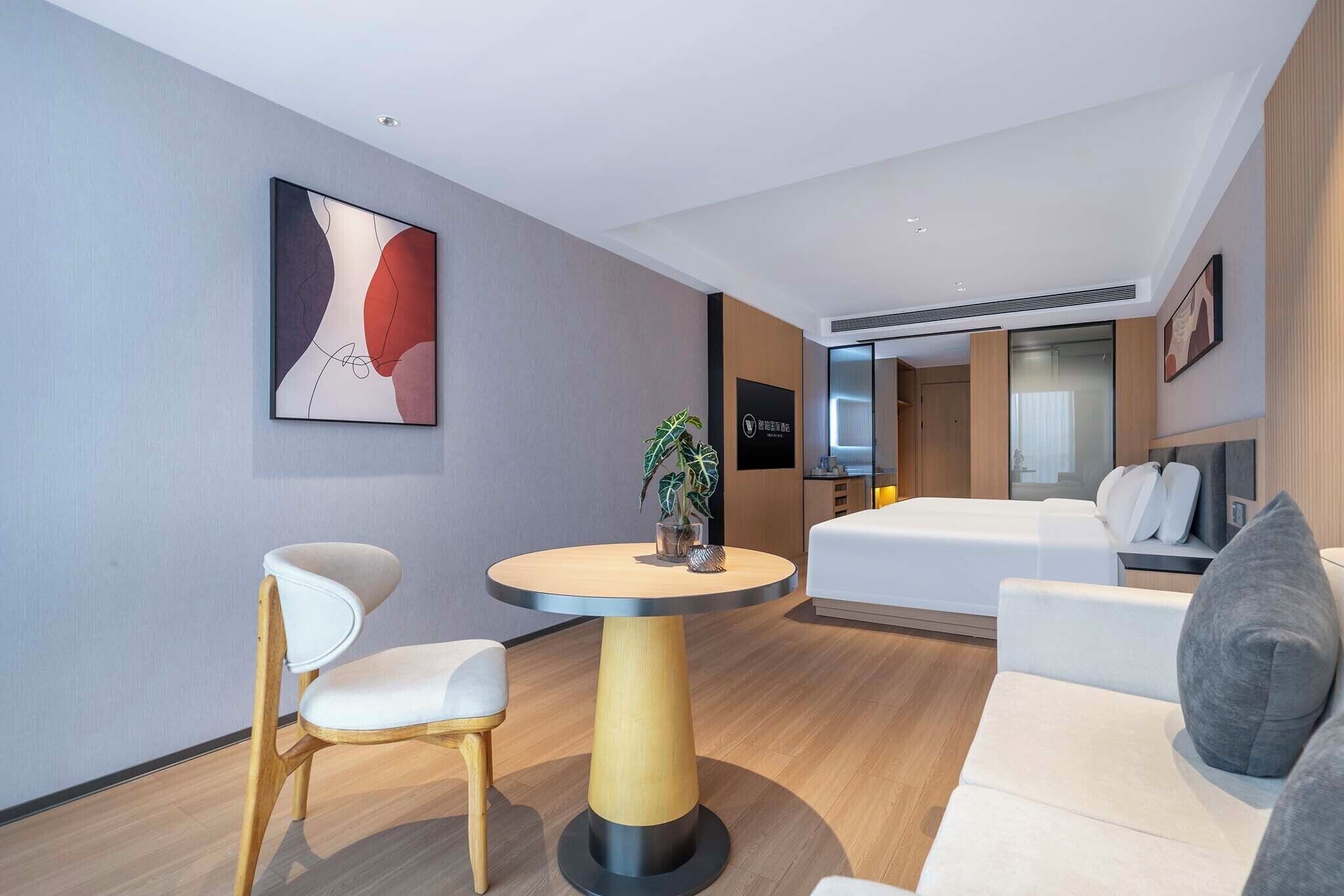 Una habitación de hotel moderna con una mesa redonda, dos sillas, un sofá y una cama.