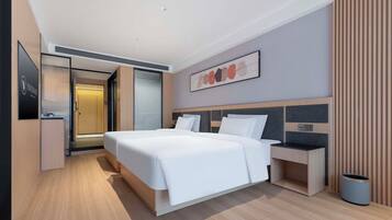 A modern hotel room with a large bed, bedside tables, a desk, and a trash bin.