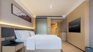 Camera d'albergo con un letto, un comodino e una TV a parete.