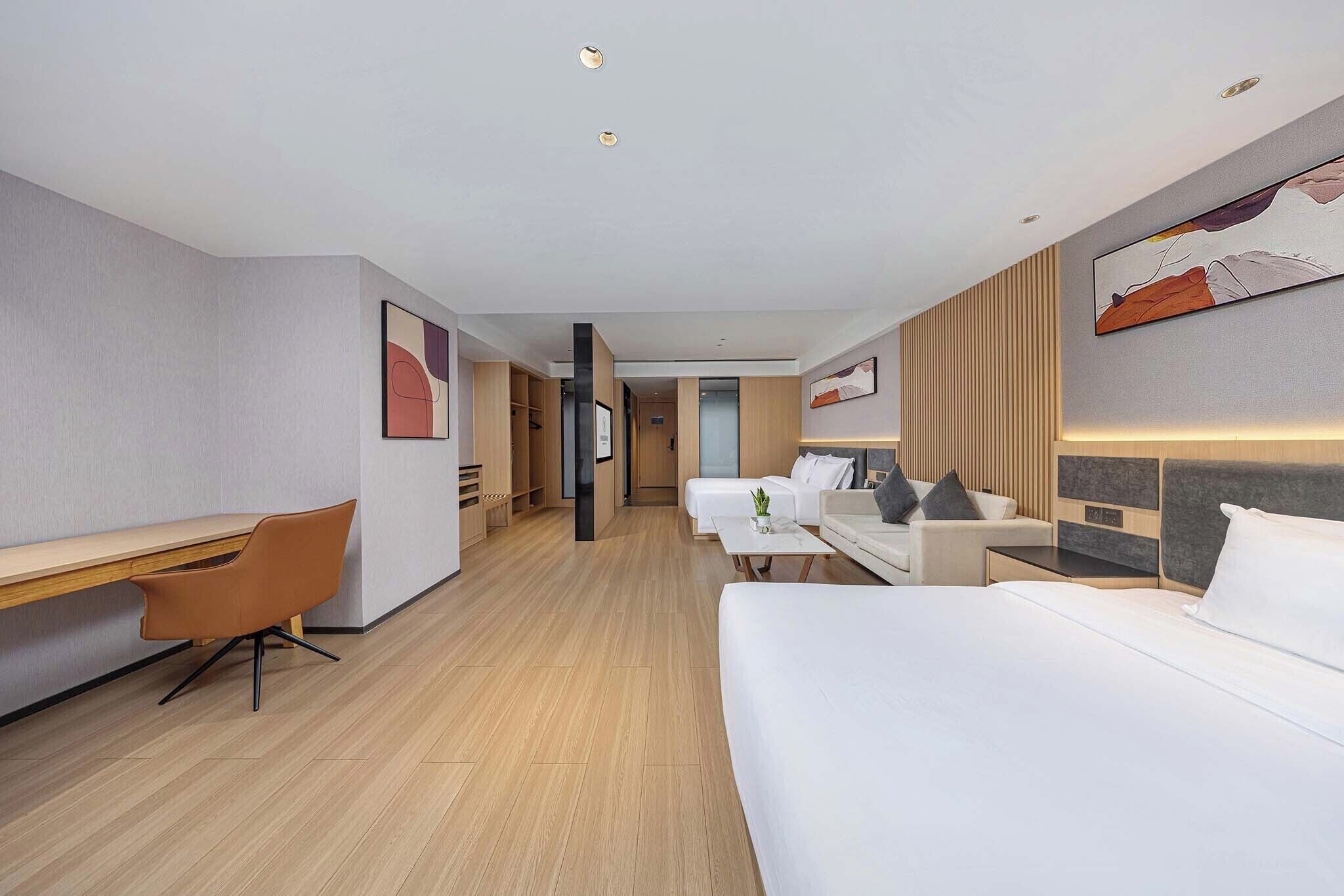 Una habitación de hotel con escritorio, dos camas y un armario.