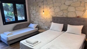 A bedroom with two beds, a stone wall, a window with a view, and a bedside lamp. - Naria Studios  (Kassandra)