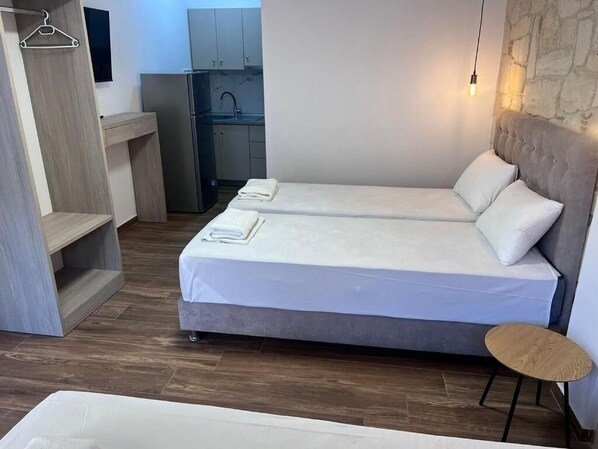 A bedroom with two beds, a small table, and a wardrobe.