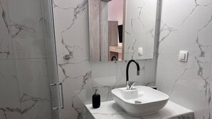 A bathroom with a white marble sink, a black faucet, and a mirror above it. - Naria Studios  (Kassandra)