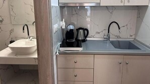 A modern bathroom with a marble sink, a black faucet, and a coffee maker. - Naria Studios  (Kassandra)