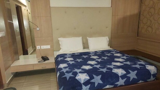 Een slaapkamer met een bed, nachtkastje, spiegel en deur.