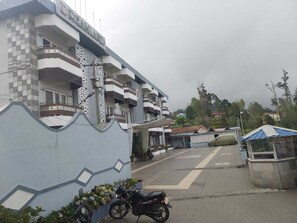 Um edifício de vários andares com design moderno, com varandas e portão fechado.