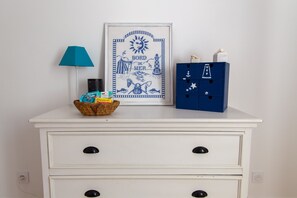 Eine weiße Kommode mit zwei Schubladen, ein gerahmtes Bild, eine Lampe und eine blaue Aufbewahrungsbox mit Verzierungen.