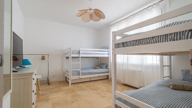 Ein Zimmer mit Etagenbetten, einem Schreibtisch mit Computer und einer Pendelleuchte.
