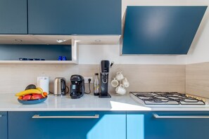 A modern kitchen with a gas stove, coffee maker, toaster, and a bowl of fruit. - Frontignan, Villa Azzura, swimming pool (Frontignan)