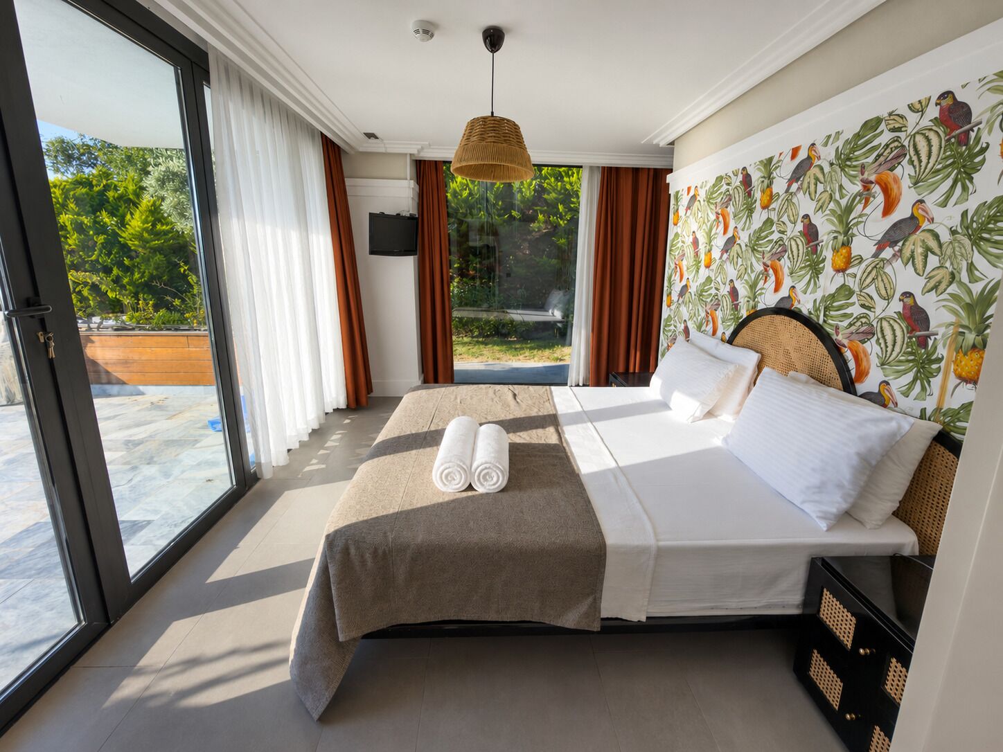 A hotel room with a bed, a large window, and a view of the outdoors.