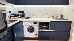 Cocina compacta con lavadora integrada, cafetera y lavabo.