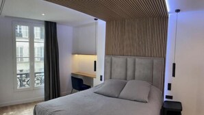 Un dormitorio moderno con una cama, un escritorio y vistas al exterior.