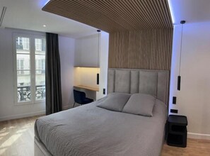 Ein modernes Schlafzimmer mit einem Bett, einem Schreibtisch und Blick ins Freie.