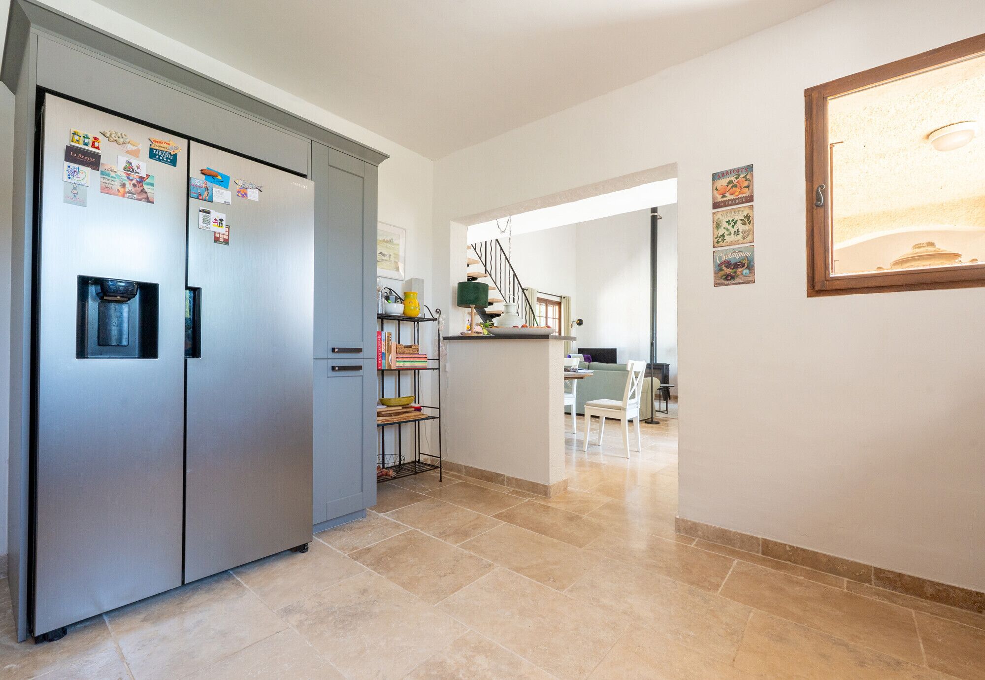 A modern kitchen with a stainless steel refrigerator, a water dispenser, and a dining area with a table and chairs.