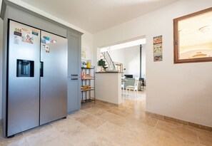 A modern kitchen with a stainless steel refrigerator, a water dispenser, and a dining area with a table and chairs. - Villa Parete Vidauban | Luxury villa with pool and large garden (Vidauban)